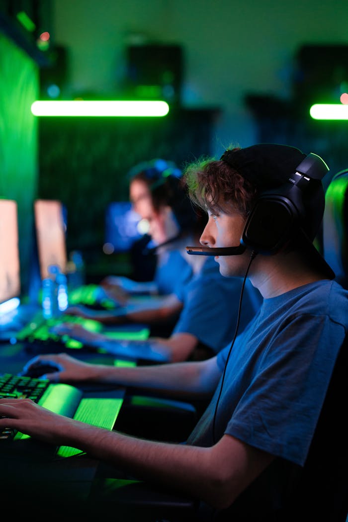 Intense gaming session with teens in a cybersport competition, illuminated by vibrant green lighting.